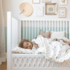 a child lying in a crib. Cam cam Sengetøj, Junior, 100x140cm - GOTS sea garden Babyseng