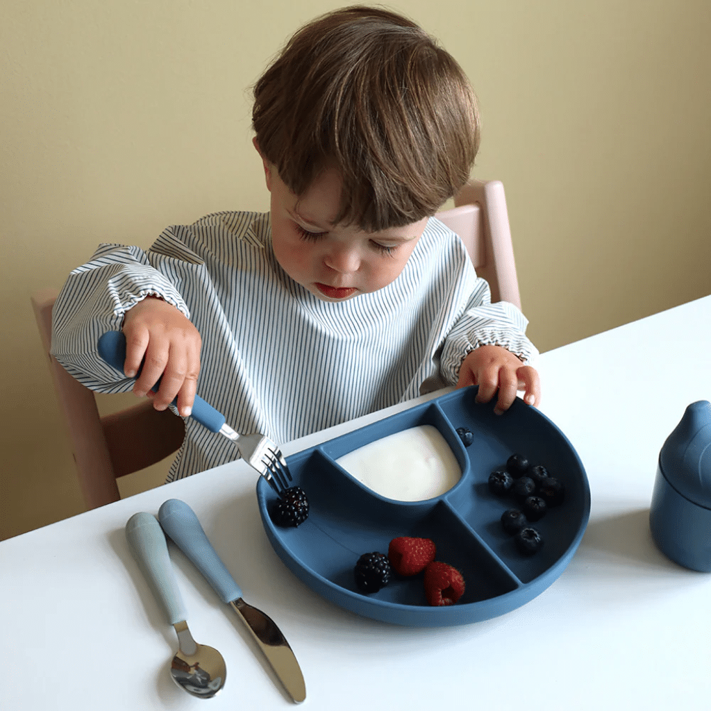 a child eating berries from a blue plate. cam cam Hagesmæk med Ærmer - Classic Stripes Blue