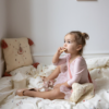 barn sidder i seng med natlampen. Carousel Night Light, Off-White - Cam Cam Copenhagen natlampe